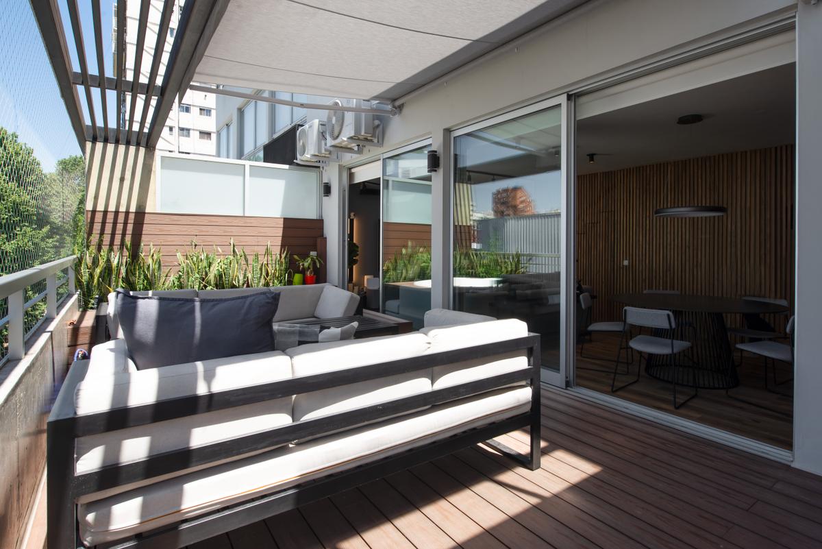 Terraço moderno com deck de madeira e sofás espaçosos — projeto Depto Arribeños, por Ayelen Mayer Arquitectura, em Buenos Aires